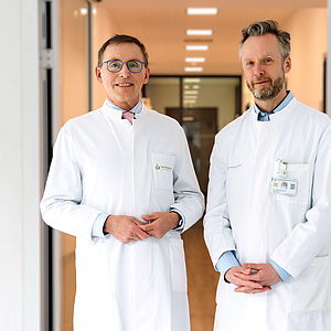 Foto zweier männlicher Ärzte in weißem Kittel auf einem Krankenhausflur